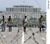 Pakistans paramilitary troops stand alert with riot gears behind a barbed wire at a road leading towards the a href=