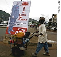 A man passes in a Freetown suburb, a poster for a href=