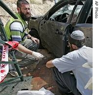 Israeli rescue workers are seen next to a car hit by a Qassam rocket fired by Palestinian a href=