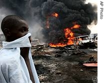 A boy covers his face as he walks past burning vehicles and a href=