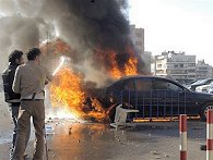 Two Lebanese pro-government supporters, extinguish a burning car after a href=