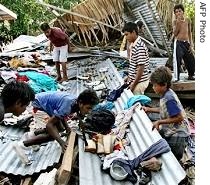 Children hunt for clothes after their village of Titiana, where 15 people died, was hit by a a href=