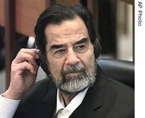 Saddam Hussein adjusts his headphones as he listens to witness a href=