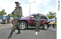 Sri Lankan Army soldiers stand guard next to bullet-ridden vehicle of a href=