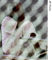 A detainee sits behind a chain-linked fence on the grounds of Camp a href=